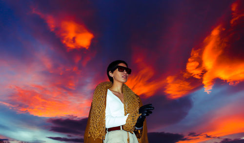 Low angle view of woman standing against orange sky