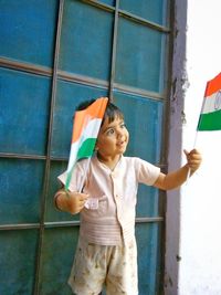 Smiling boy holding flags outside house