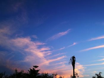 Low angle view of silhouette trees against blue sky