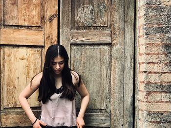 Portrait of a young woman standing against wall