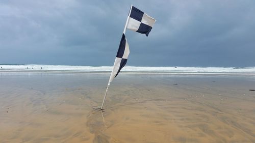 Lifeguard flag on beach against sky