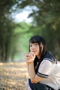 Portrait of young woman against trees