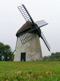 Traditional windmill on field against sky