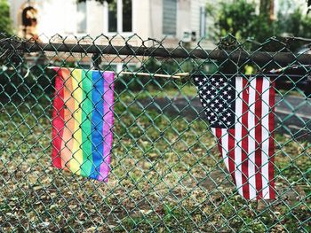 Rainbow and american flags hanging on chainlink fence