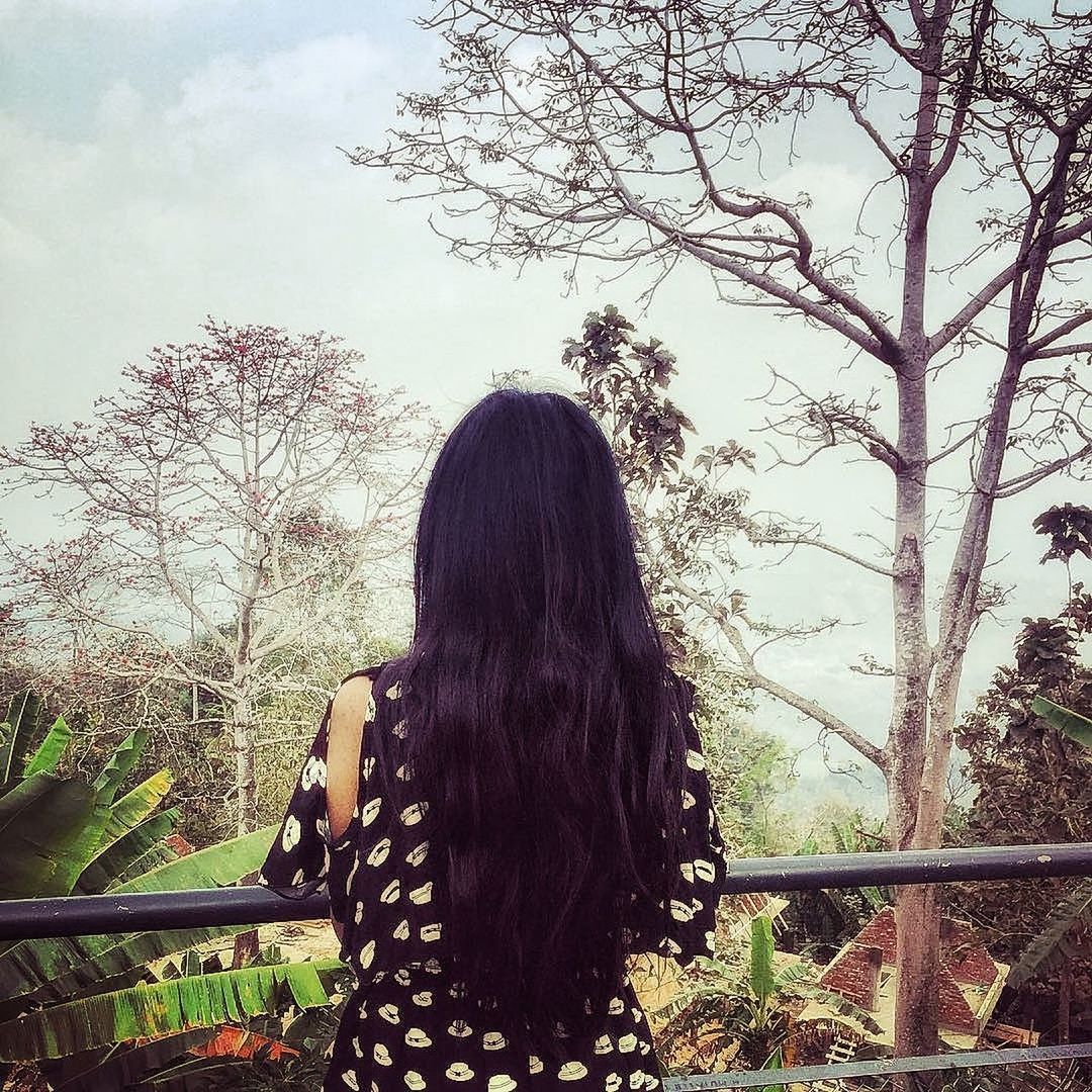 REAR VIEW OF WOMAN STANDING BY BARE TREE