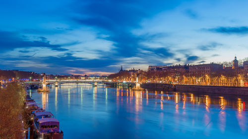 Illuminated bridge over river against sky at night