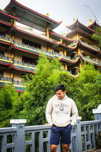 Portrait of young man standing against building