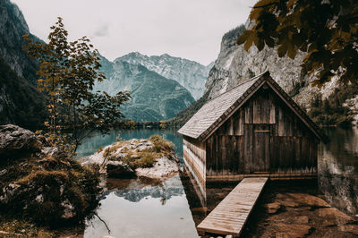 House by lake and mountains against sky