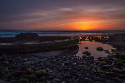 Abandoned built structure at beach against sky during sunset