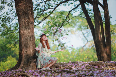 Woman sitting on tree trunk