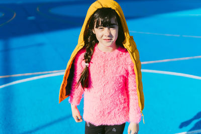 Cute girl wearing padded jacket while standing on sports court