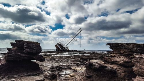 Rock formation on beach against sky