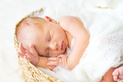 Cute baby sleeping in basket on bed