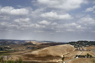 Scenic view of road amidst field against sky