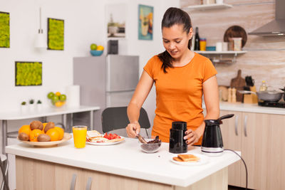 Young woman standing on table at home