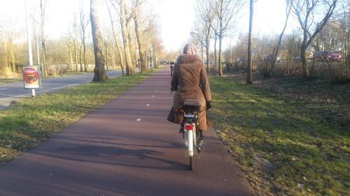 Rear view of man riding bicycle on road