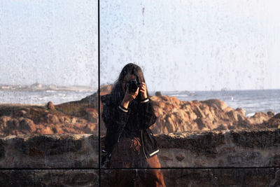 Woman photographing by sea