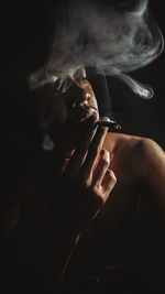 Man smoking cigarette against black background