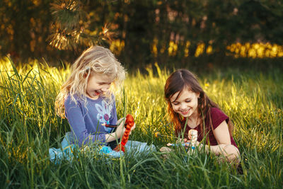 Happy children girls playing dolls in park.  kids sitting in grass on meadow playing toys