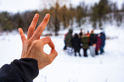 Cropped image of person hand on snow during winter