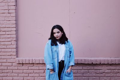 Portrait of young woman standing against wall