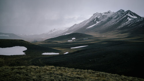 Scenic view of snowcapped mountains against cloudy sky