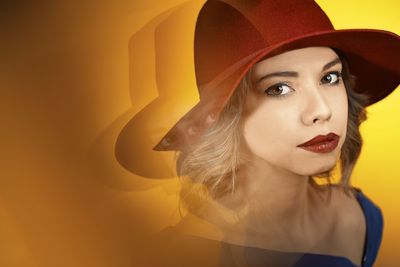 Digital composite image of young woman wearing hat against yellow background