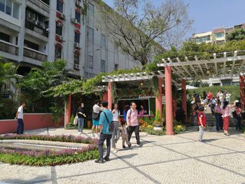 People on sidewalk by buildings in city