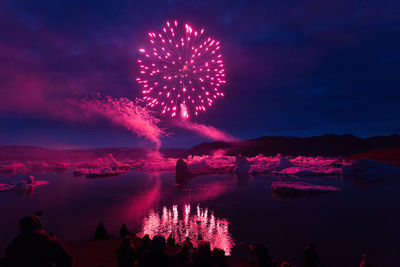 Firework display over lake at night