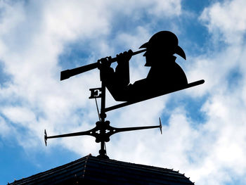 Low angle view of silhouette man on roof against sky