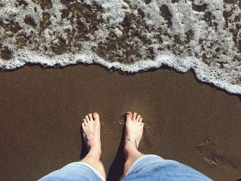 Low section of man standing on shore at beach