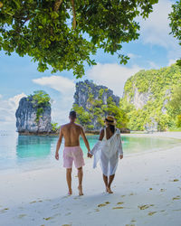 Rear view of woman standing at beach against sky