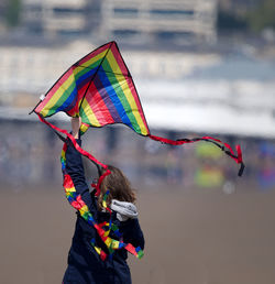 Rear view of woman holding multi colored umbrella