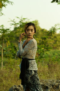 Girl standing on field against trees