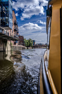 Bridge over river by buildings in city against sky