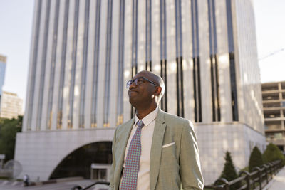 Mature businessman wearing eyeglasses standing in financial district