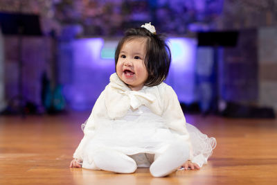 Portrait of cute girl sitting on hardwood floor at home