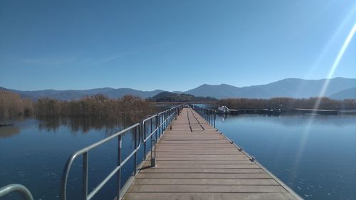Pier over lake against blue sky
