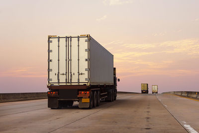 Bus on road against sky during sunset