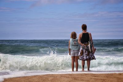 Rear view of women standing on beach