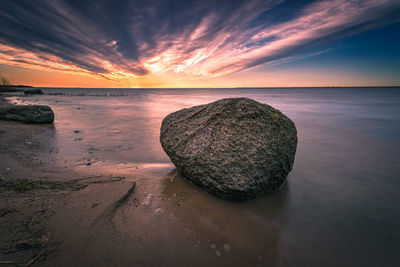 Scenic view of rocks on beach against sky during sunset
