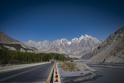 Road leading towards mountains against blue sky
