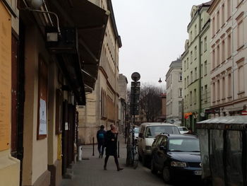 People walking on street amidst buildings in city against clear sky