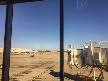 People at airport against sky seen through glass window