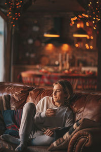 Portrait of candid authentic smiling handsome boy teenager using mobile phone at xmas home interior