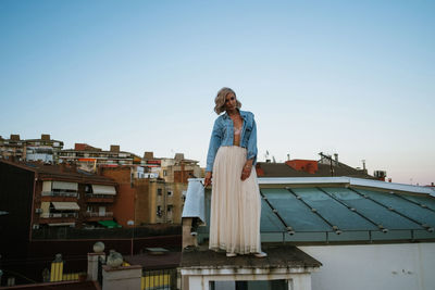 Woman standing by buildings against clear sky