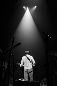 Rear view of male guitarist performing on stage during concert