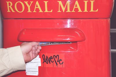 Close-up of hand holding red mailbox