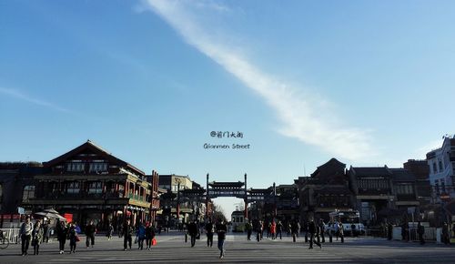 People in town square against sky in city