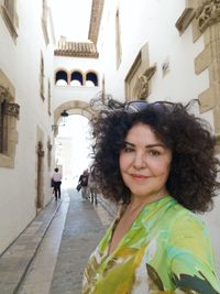 Portrait of young woman standing against building